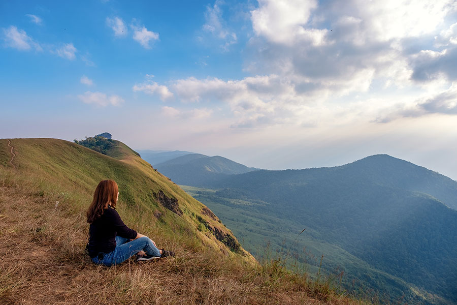 A woman sitting and watching sunset with mountains view in the evening